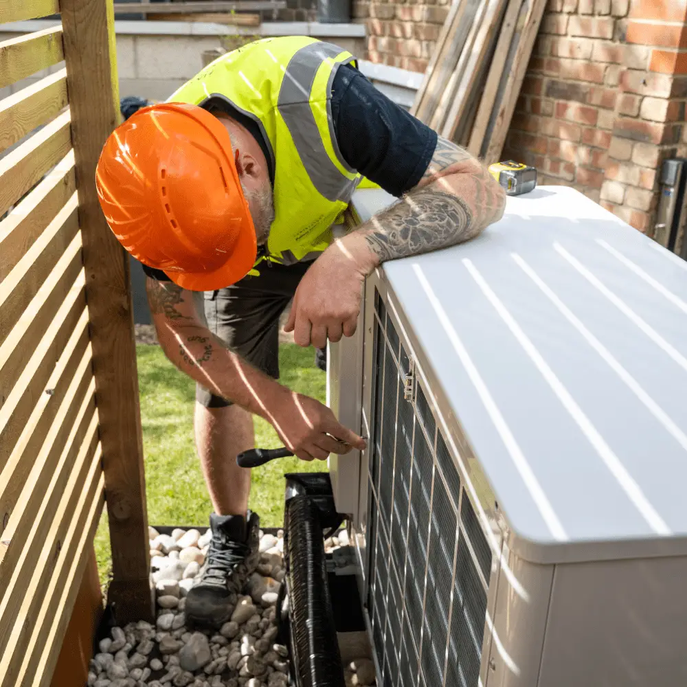 HVAC engineer installing air source heat pump with insulated pipework.