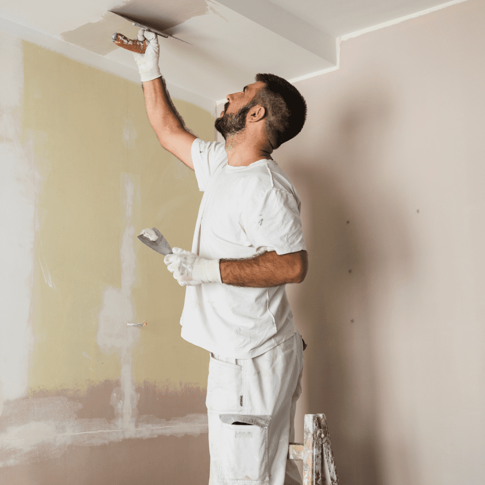 Plasterer skimming a ceiling with hawk and trowel.