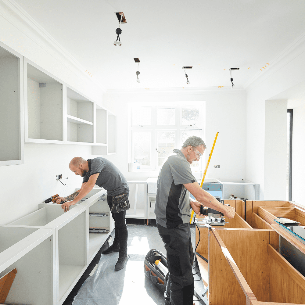Joiners fitting kitchen cabinets in a bright modern home.