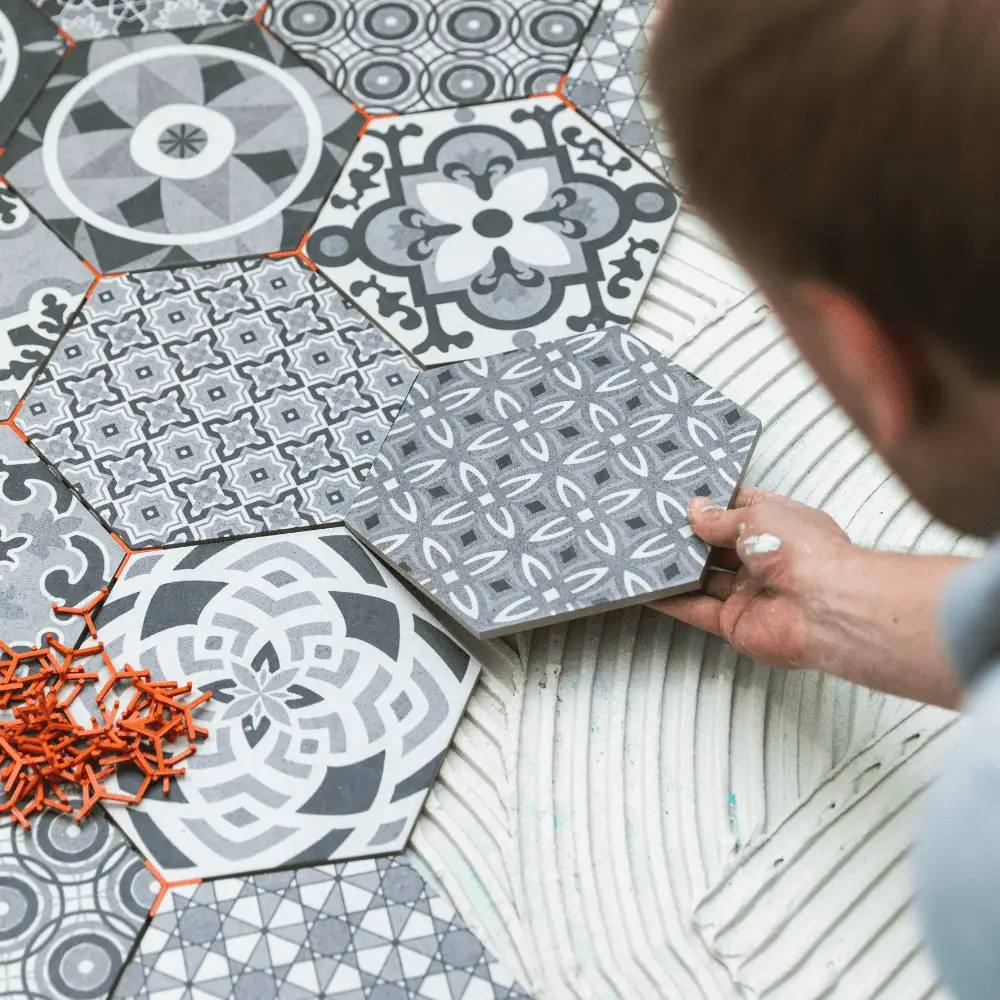 Tiler placing patterned hexagon floor tiles in geometric layout.